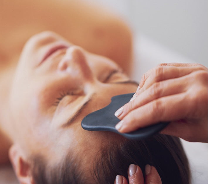 Gua Sha facial massage on woman's forehead
