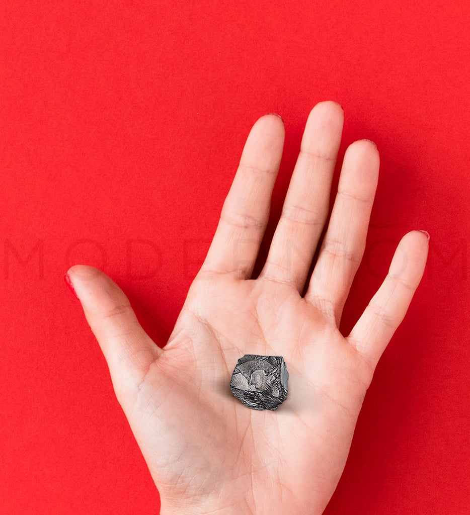 ElitShungite stone held in hand against red background