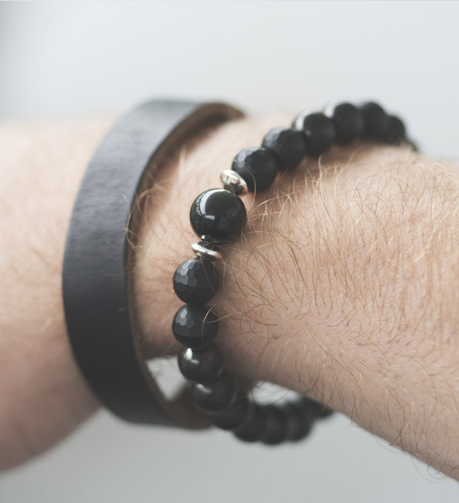 Black beaded bracelet and leather band on wrist