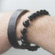 Load image into Gallery viewer, Black beaded bracelet and leather band on wrist