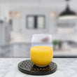 Load image into Gallery viewer, ShgntDisk coaster with glass of orange juice