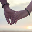 Load image into Gallery viewer, Couple holding hands, wearing 8-10mm bracelets for web therapy.