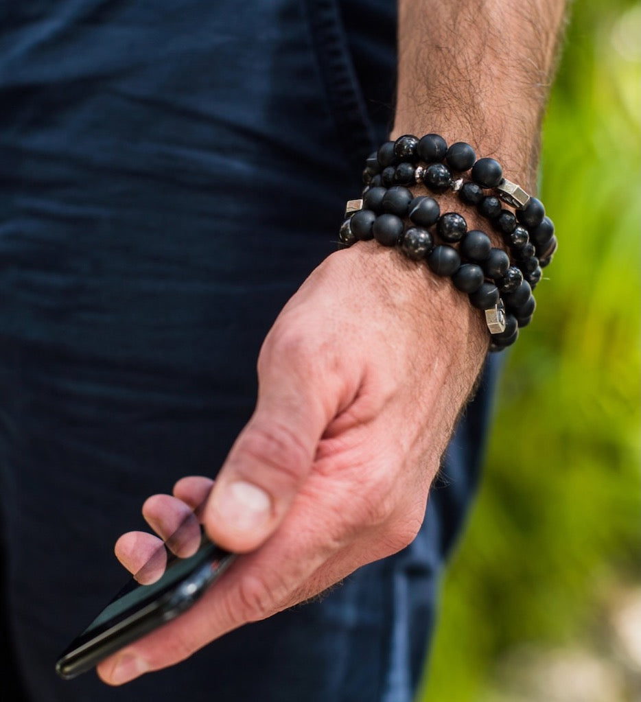 Man's hand with black beaded bracelets and phone (dzipic2FINAL)