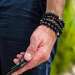 Load image into Gallery viewer, Man's hand with black beaded bracelets and phone (dzipic2FINAL)