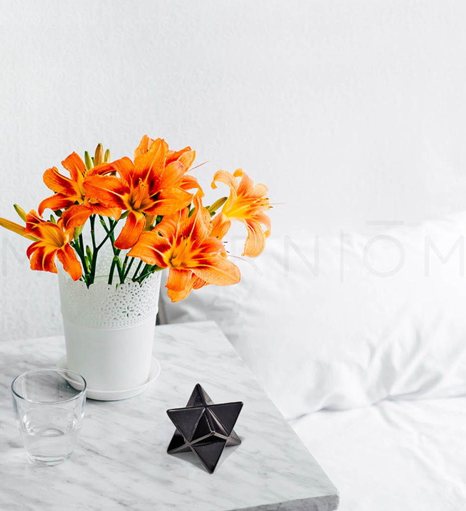 Orange lilies, glass, and Merkaba on bedside table