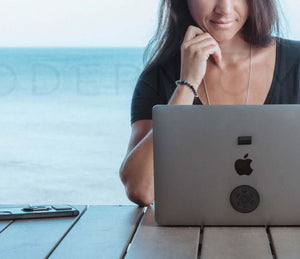 Woman using laptop with EMF shield plates by the ocean
