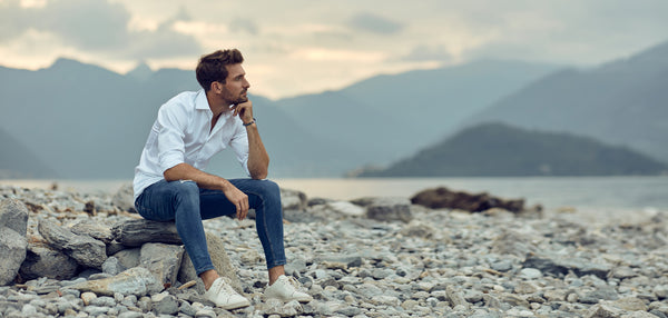 Man wearing bracelet sitting by lake, desktop slider image.